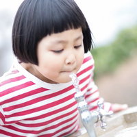 公園の水飲み場で水を飲む前髪パッツン少女の写真