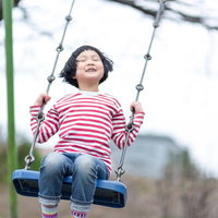 公園のブランコでハッピーにはしゃぐ子供たちの笑顔の写真