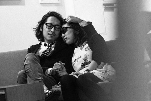 ソファに座り眼鏡の男性の肩に頭を寄せる花柄の服の女性