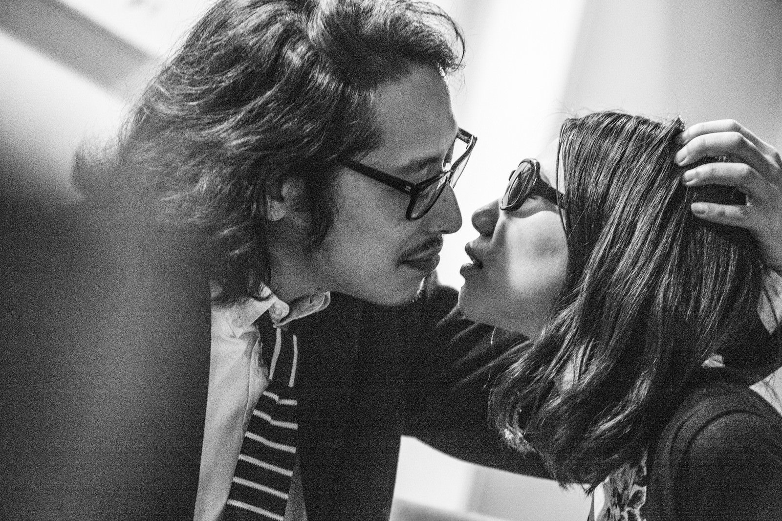 向かい合う眼鏡の2人の白黒写真で縞模様ネクタイと右手を頭に添えるポーズ［モデル：ゆうせい］