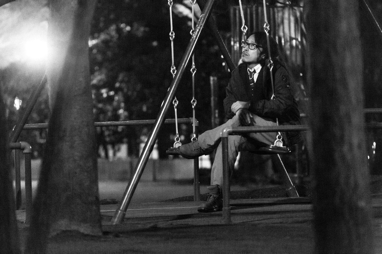 夜の公園でブランコに座るスーツ姿の男性