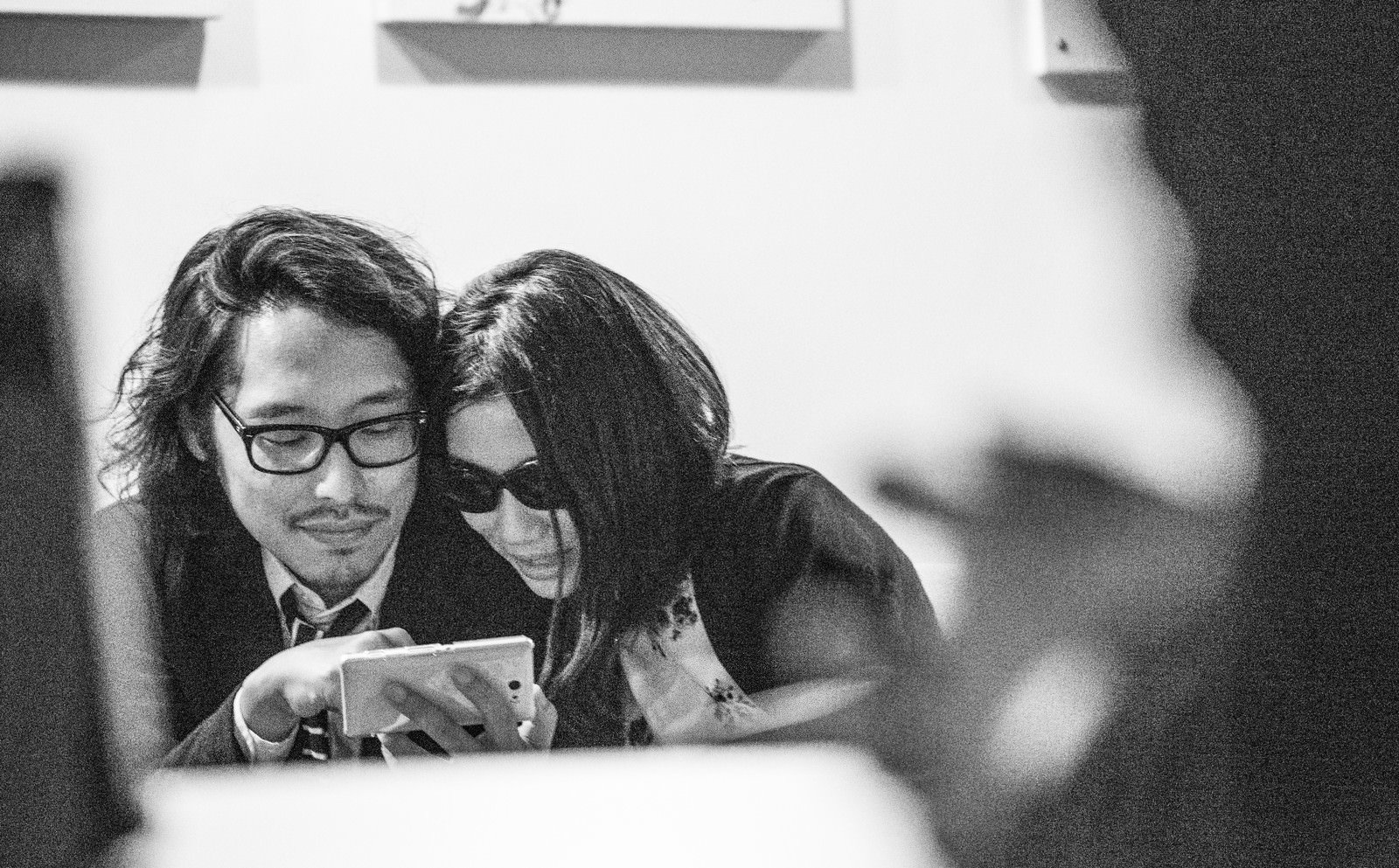 男女がスマートフォンを一緒にのぞき込む［モデル：ゆうせい］