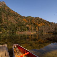 晩秋の上高地・明神池に浮かぶ赤いカヌーと北アルプスの黄葉の写真