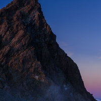 夕暮れ時、霧に覆われた槍ヶ岳の岩壁と北アルプスの景観の写真