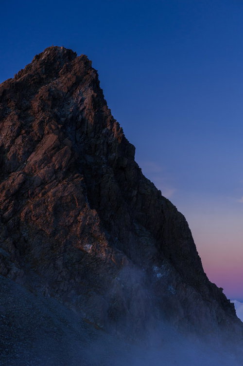 夕暮れ時、霧に覆われた槍ヶ岳の岩壁と北アルプスの景観