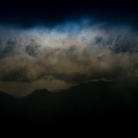 危険な雲行きで暗くなる北アルプスの山々と雨雲の写真