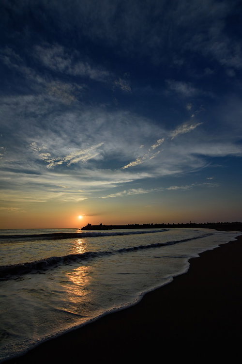朝焼けの海岸に打ち寄せる波とレイライン