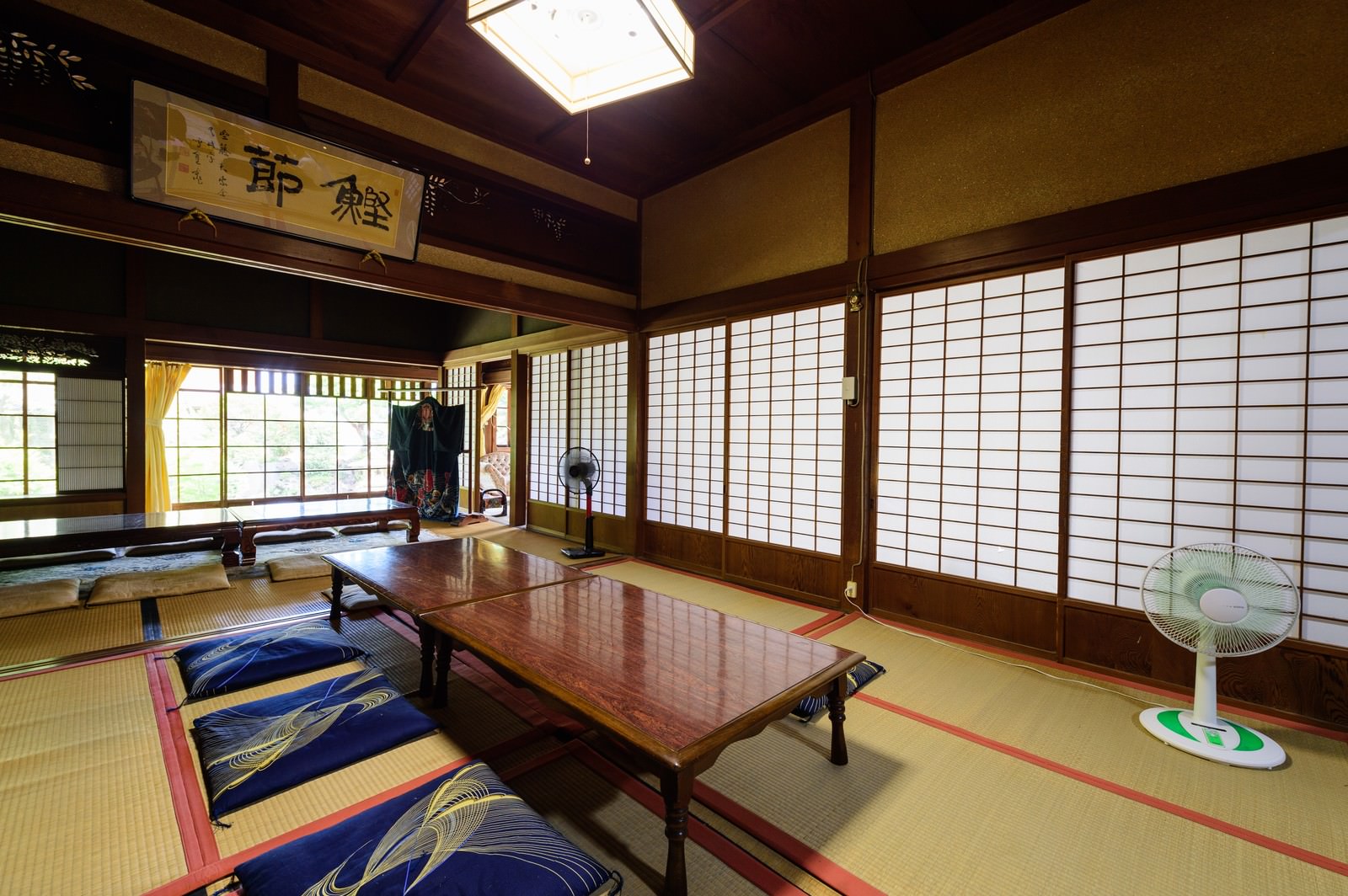畳の上に青い座布団が並ぶ古民家の和室、障子から自然光が差し込む