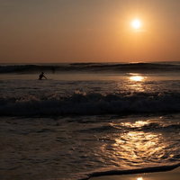 朝焼けの波打ち際に挑むサーファー達（千葉県一宮町）の写真