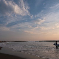 朝焼けに染まる一宮海岸で波打ち際に立つサーファー達の写真