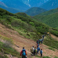 乗鞍新登山道から望む北アルプス稜線を歩く登山者たちの写真