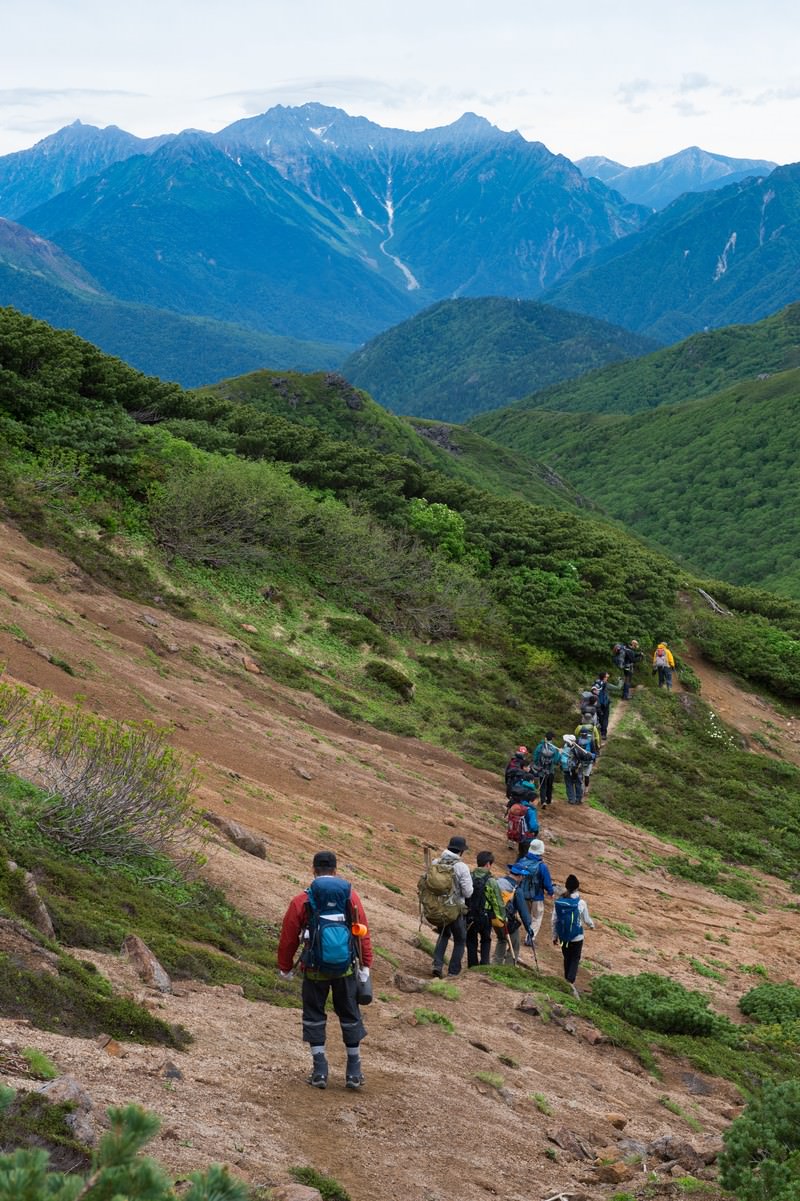 乗鞍新登山道を列で歩く登山者と北アルプスの稜線