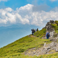 夏の青空と白い雲が映える乗鞍新登山道の稜線を歩く登山者の写真