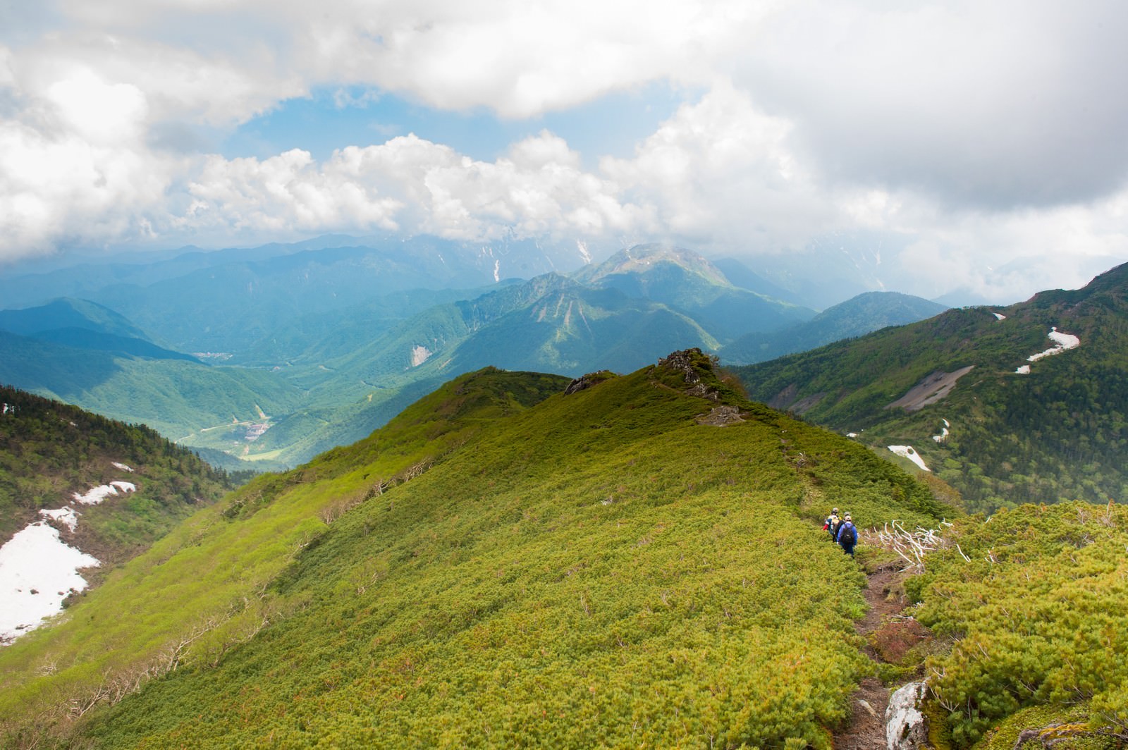 乗鞍新登山道の尾根を歩く2人のハイカーと北アルプス