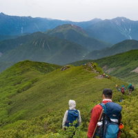 焼岳越しに笠ヶ岳を望む乗鞍新登山道と登山者の写真