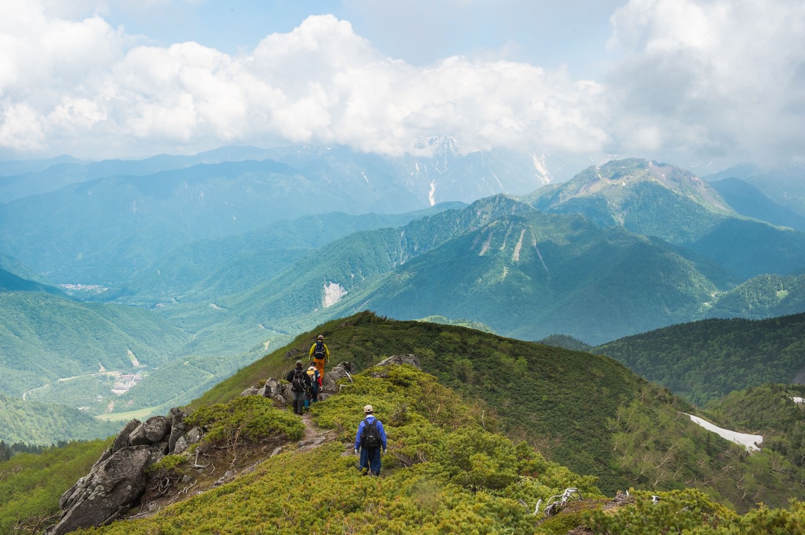 稜線を歩く登山者と焼岳・平湯温泉の眺め