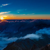 槍ヶ岳山頂から見下ろす夕暮れの北アルプスの山々と雲海の写真