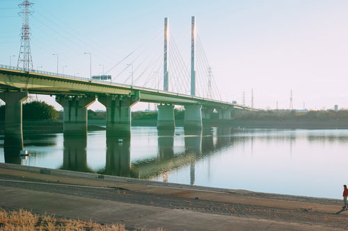 陽が差し込む河川敷の橋と堤防沿いの風景