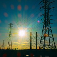 夕焼けに浮かぶ鉄塔と送電線のシルエットの写真
