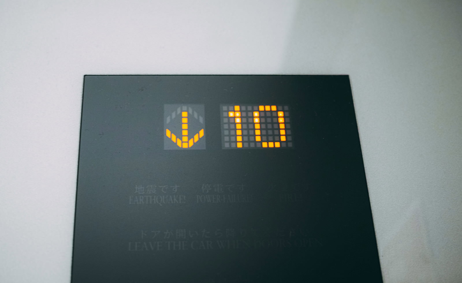 エレベーターの緑色の表示パネルに黄色で10の数字が表示されている