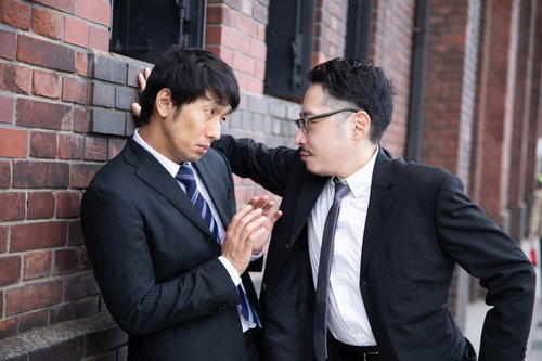 レンガ壁に手をつく壁ドンをするスーツ姿の男性