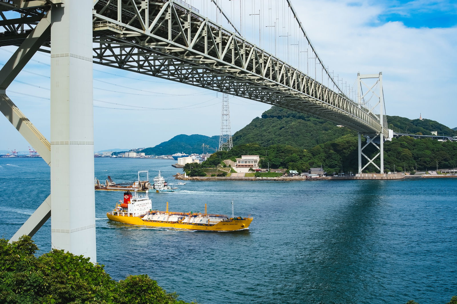 関門橋の下を通過する黄色い貨物船と関門海峡の風景