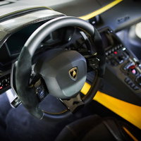 ランボルギーニの黒革ステアリングと高級車の運転席の写真