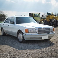 砂利敷きの青空駐車場に停めるベンツの写真