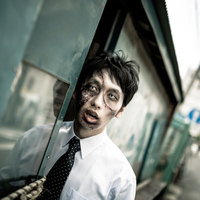 物陰から覗くゾンビメイクのネクタイ姿の男性の写真