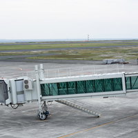 空港ターミナルに設置された到着機を待つボーディングブリッジの写真