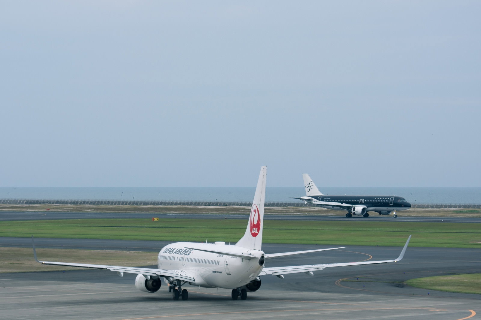 山口宇部空港の滑走路で離陸準備をする白い旅客機と着陸機