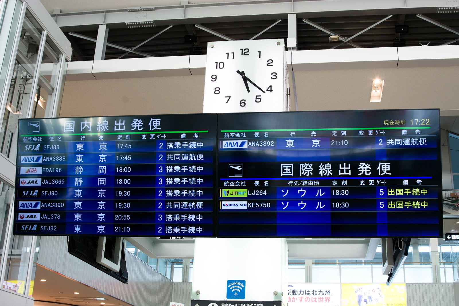 青い背景に白文字で便名と時刻が表示された地方空港の出発便案内電光掲示板