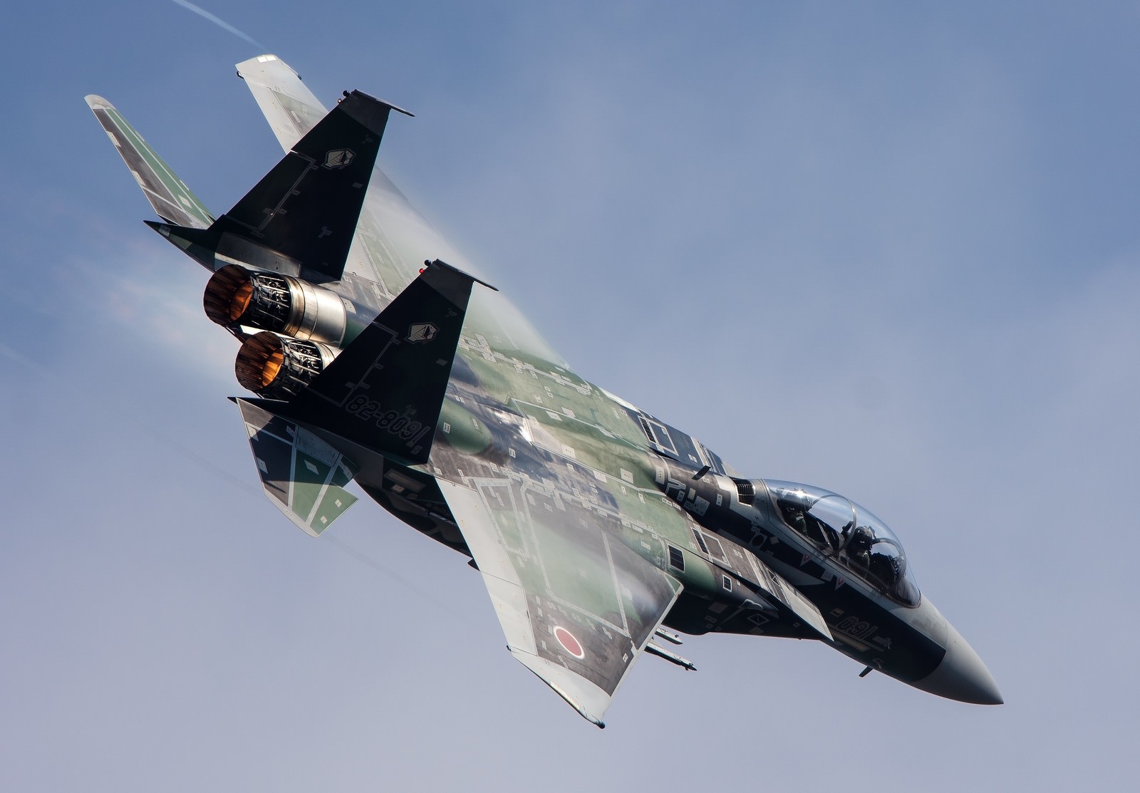 黒い双発戦闘機が下から見上げた角度で上昇中。双発エンジンから橙色の火炎を噴出し、白い翼が青空に映える。