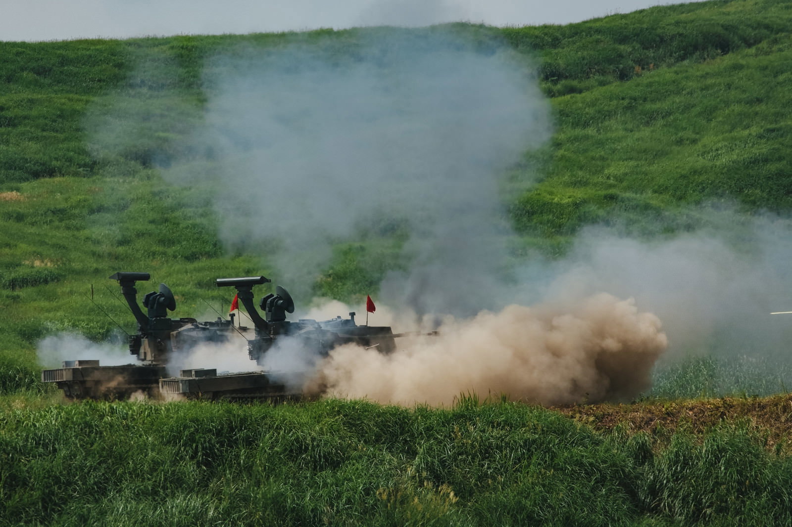 緑地で射撃訓練を行う87式自走高射機関砲と巻き上がる砂埃