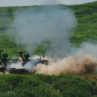 87式自走高射機関砲の射撃で巻き上がる砂埃の写真