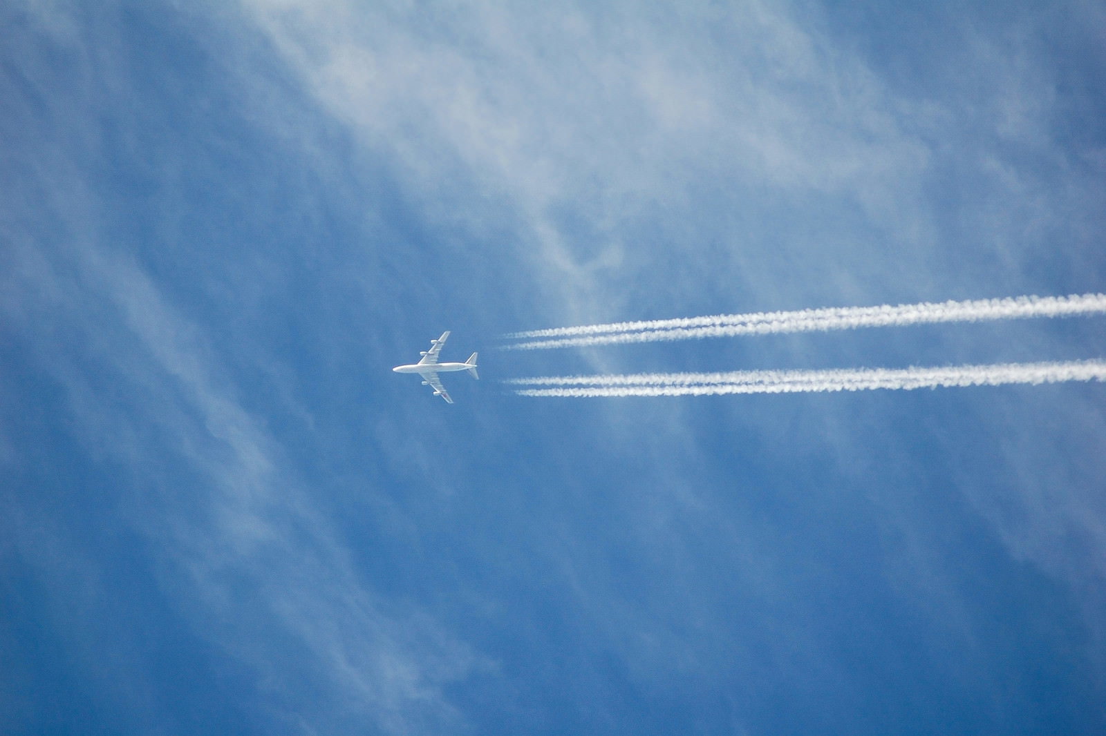 青空を飛ぶ旅客機が4本の飛行機雲を引いている