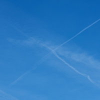 飛行機雲が交差して消えていくの写真