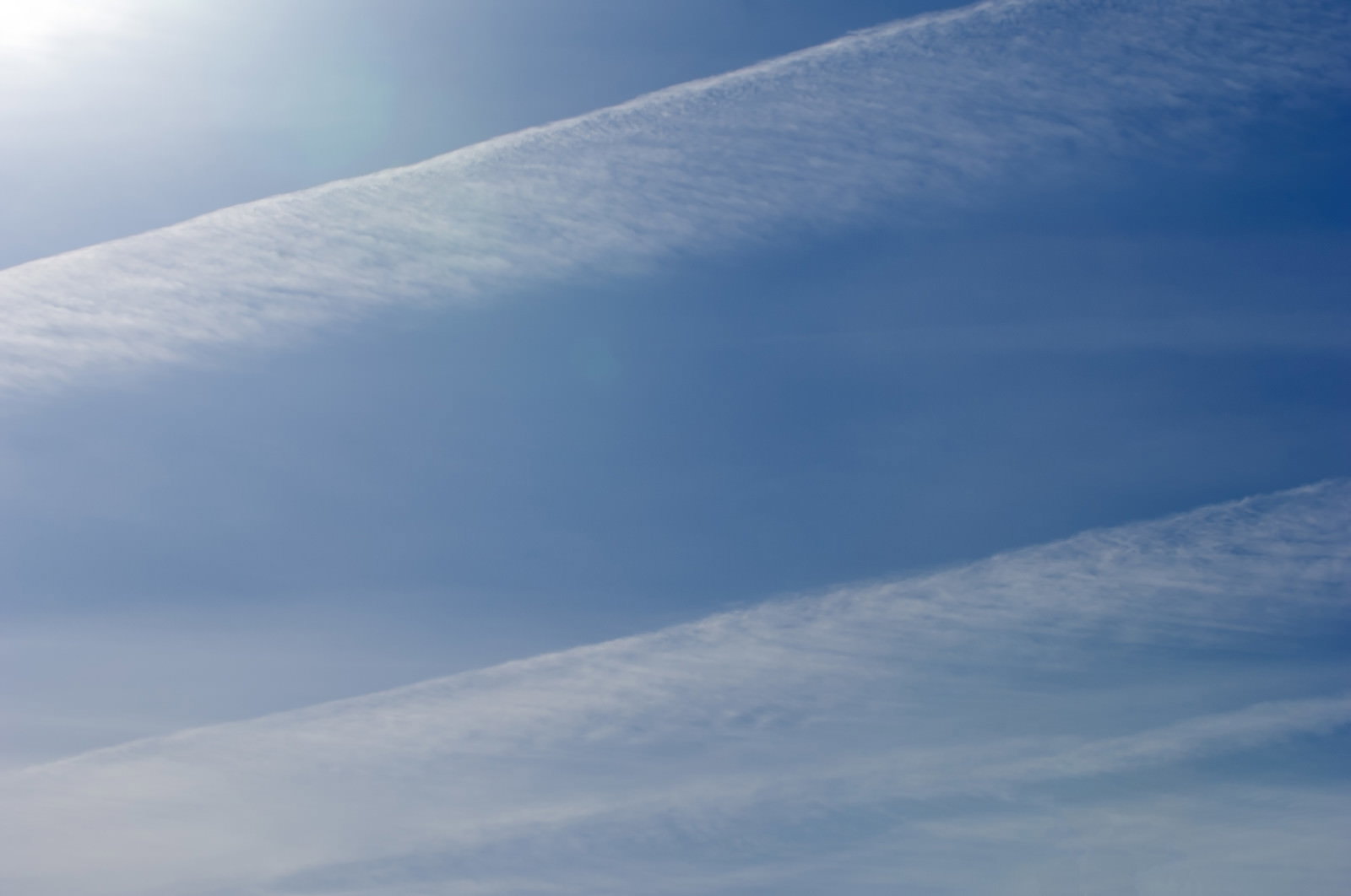 青空に飛行機雲が薄れて消えていく