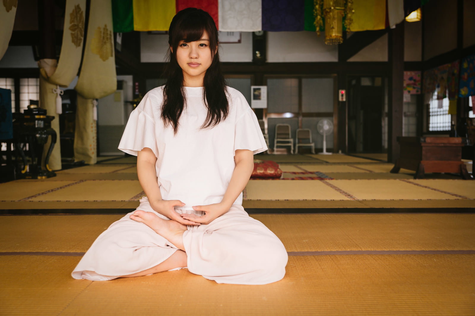 座禅堂の畳の上で瞑想する白い服の女性［モデル：河村友歌］
