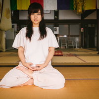 白いシャツで座禅を組む女性、畳敷きの座禅堂で瞑想の写真