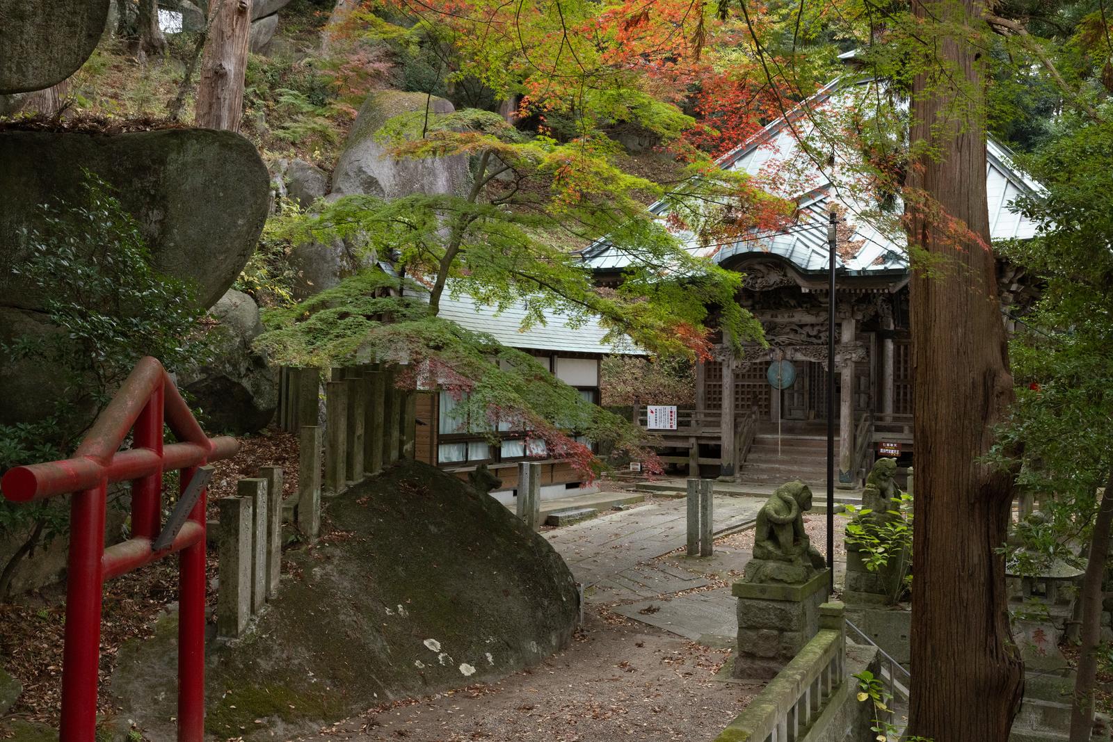 苔むした石灯籠と秋色の樹々に囲まれた岩角寺の木造お堂