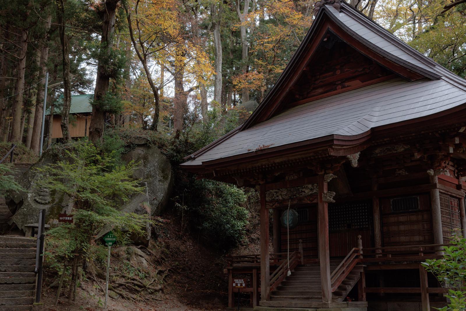 本宮市の岩角山にある岩角寺の那智観音堂、秋の雑木林に囲まれた赤い柱の木造建築