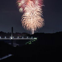 三春町の夜空に舞う打ち上げ花火と橋の夜景の写真