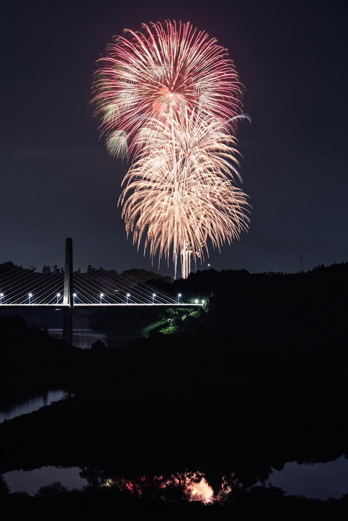 三春町の夜空に舞う打ち上げ花火と橋の夜景