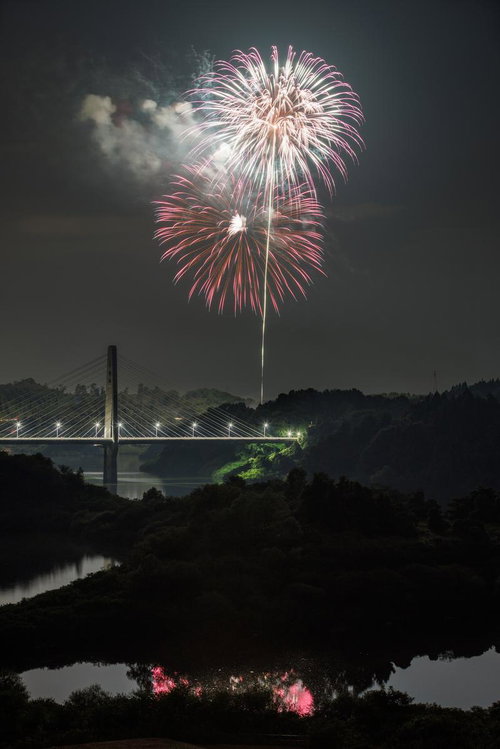 夜空に咲く三春花火と斜張橋、水面に映る打ち上げ花火