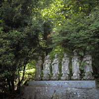 緑に囲まれた東堂山満福寺の境内に並ぶ六地蔵の写真