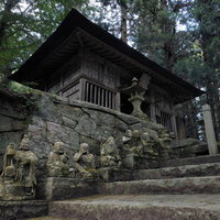 東堂山満福寺の石段に並ぶ羅漢の石像と黒木造建築の写真