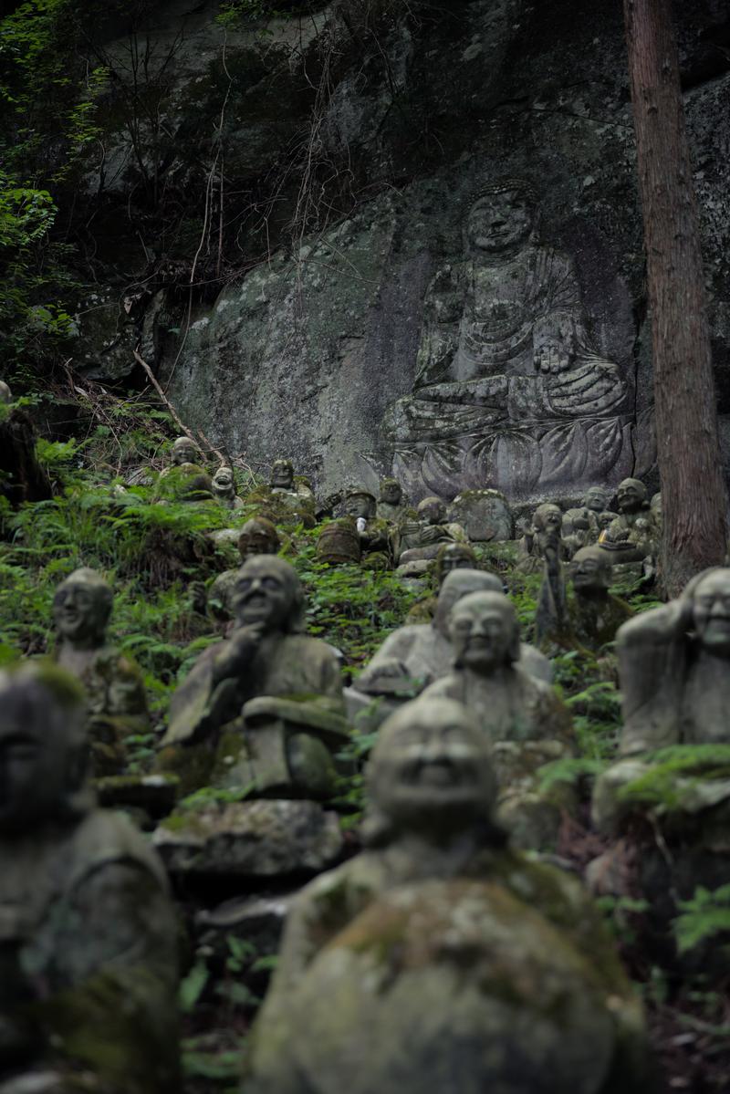 東堂山満福寺の苔むした羅漢石像群と岩壁に彫られたお釈迦様の像