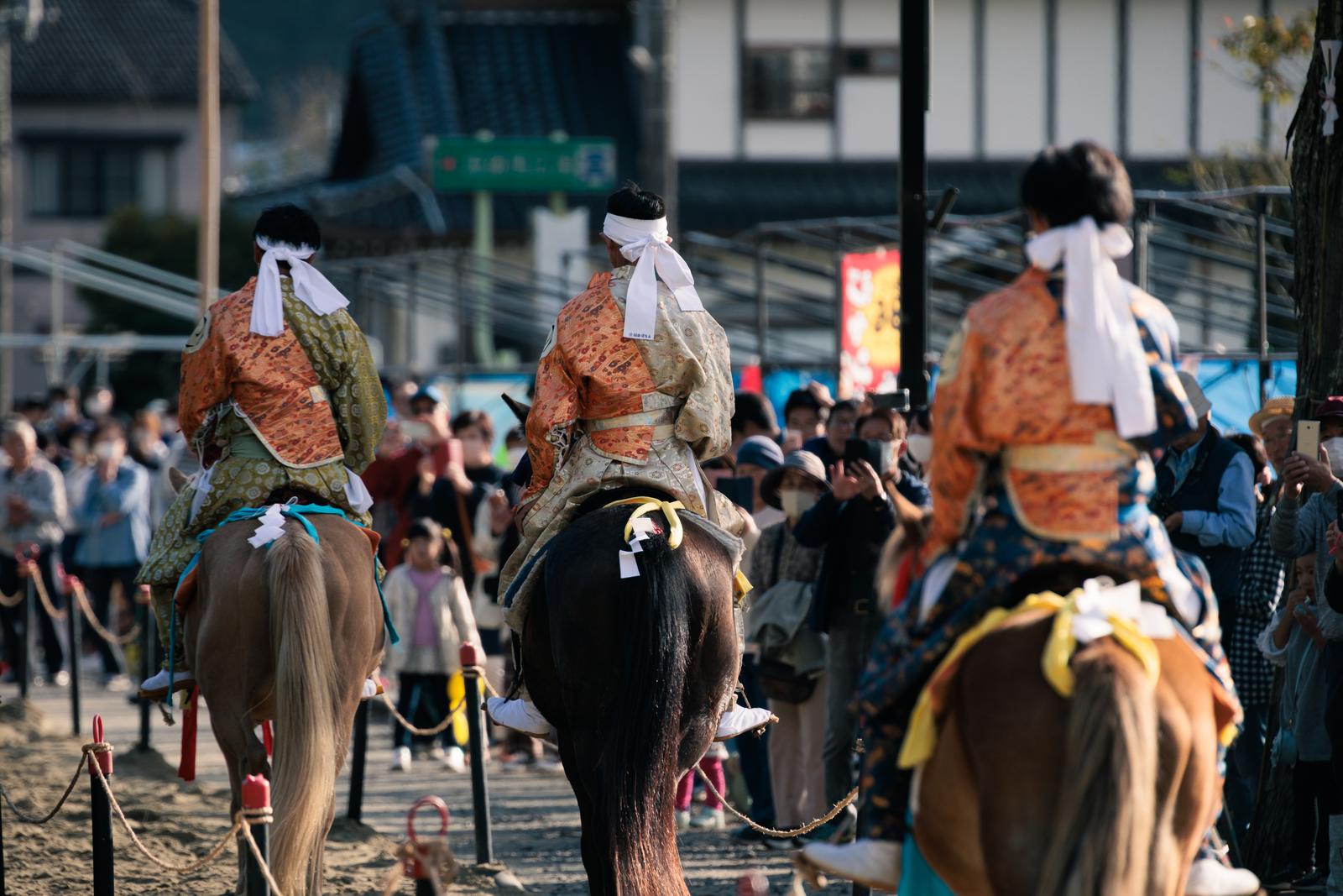 流鏑馬の馬上で白い襷をつけた3人の騎士、古殿八幡神社の神事の写真 