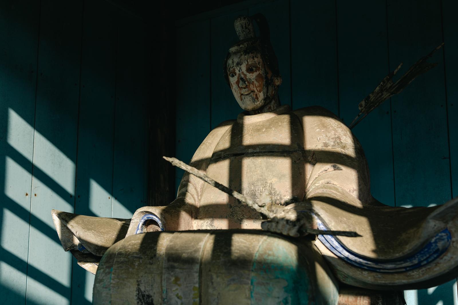 古殿八幡神社の境内に立つ、風化した白い石造りの武士像